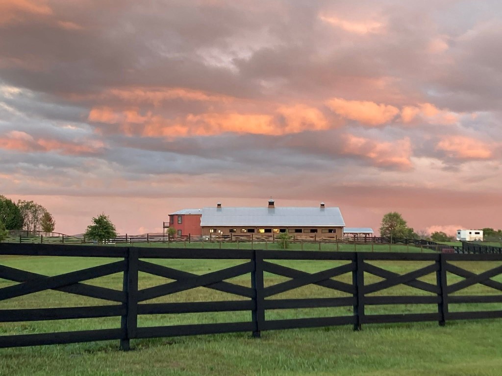 Barn and pastures at Greenbrier Equine Farm under a sunset sky